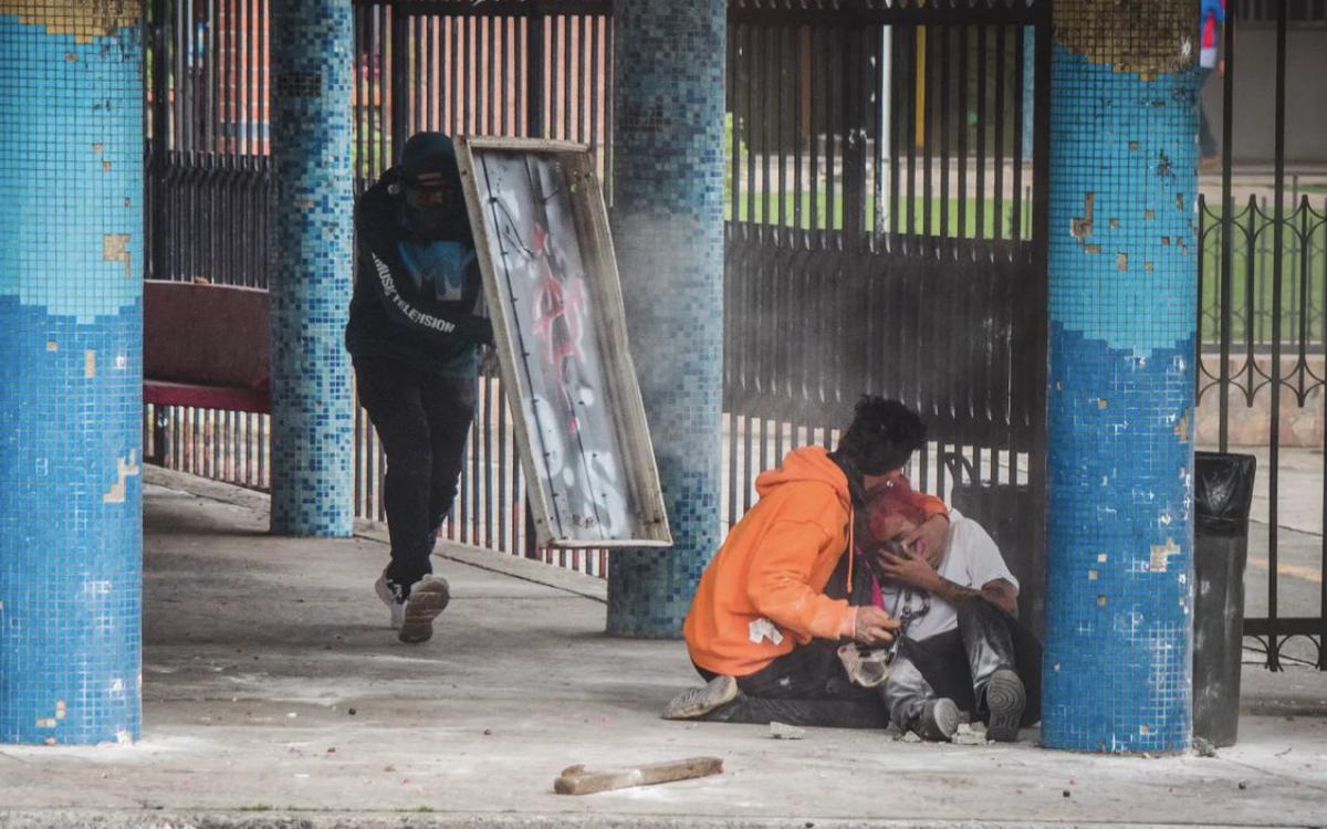 Estudiante tendida en el piso tras lesión causada por bala de goma.