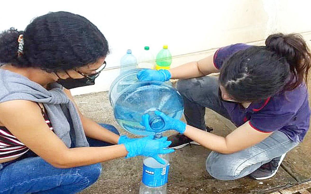 Las estudiantes Valeria Mosquera y Gretchell Regalado, durante la recolección de muestra de aguas residuales